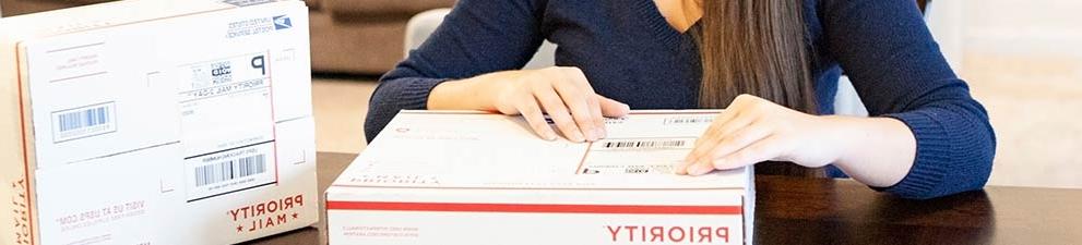 Woman attaching a shipping label to a Priority Mail box.